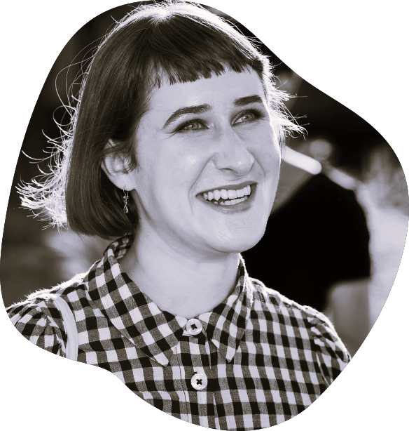 The Peerclass host, Jasmin Allenspach, beams in a black-and-white photo, wearing a gingham shirt and a short bob with bangs